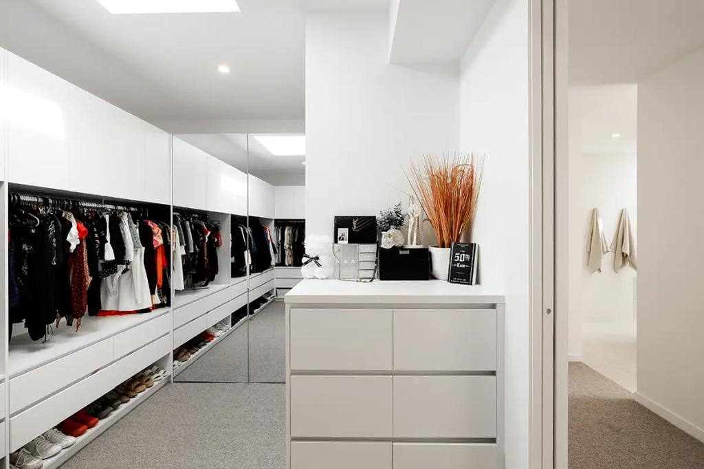 Project Vuse (A modern, well-organized walk-in closet with white built-in cabinets and large mirrors)