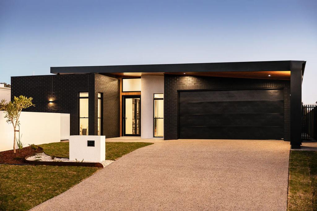 Project Ward (A modern house with a black brick exterior, large windows, and a spacious driveway at dusk)