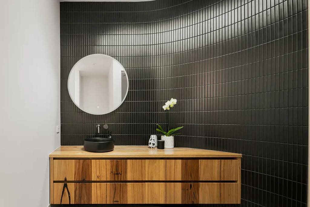 Project Treevue (A modern bathroom with a wooden vanity and round mirror)