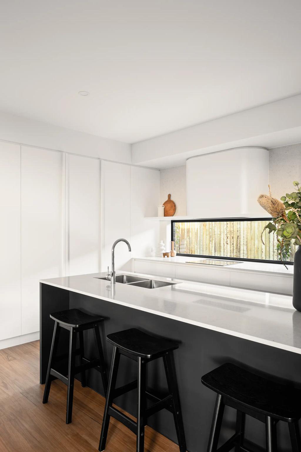 Project Ward (Modern kitchen with white cabinets, black stools, a white island, and a sink under a large window)