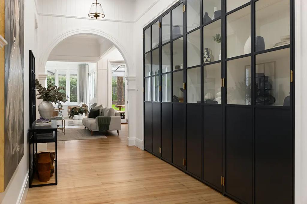 Project Franklin (Black display cabinetry lines hallway leading to sunlit lounge.)