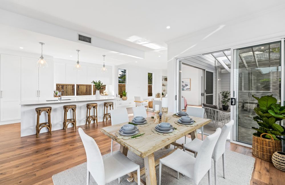 Project Campbell (White kitchen island with timber stools, glass pendants and a light-wood dining table)
