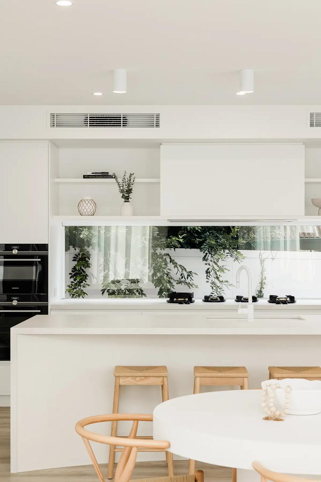 Project Vuse (A modern kitchen with white cabinets and countertops and a round dining table with wooden chairs)