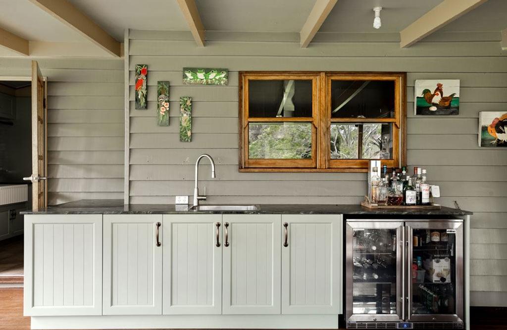 Outdoor kitchen sink with metal faucet and light green cabinet