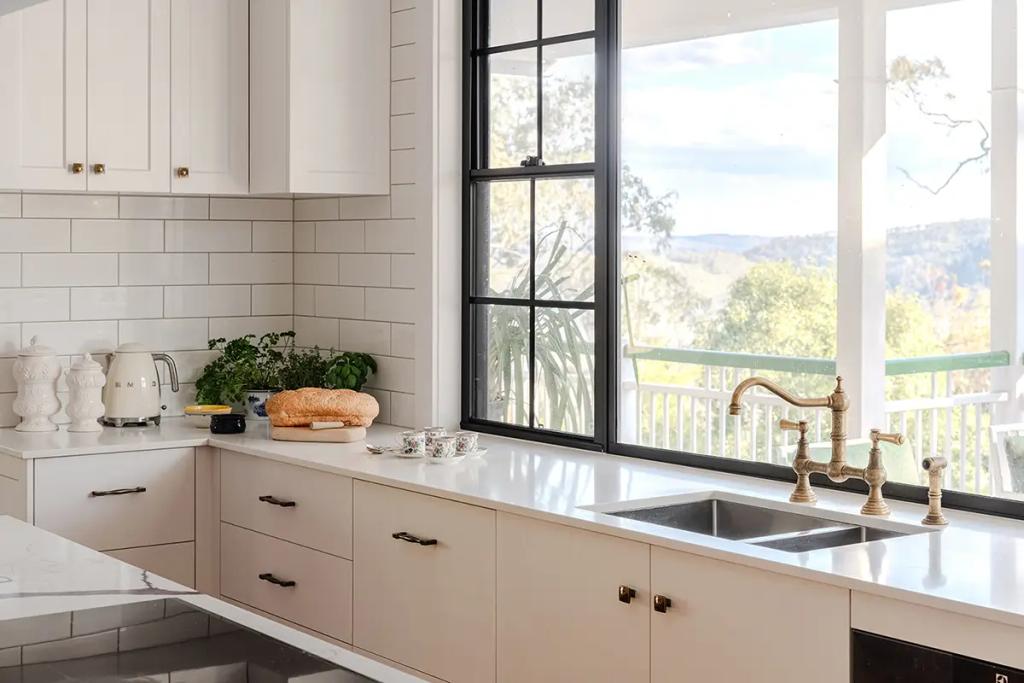 Project Coral Sea (Modern kitchen with large window, white cabinets, subway tile, brass faucet, and bread on the counter)