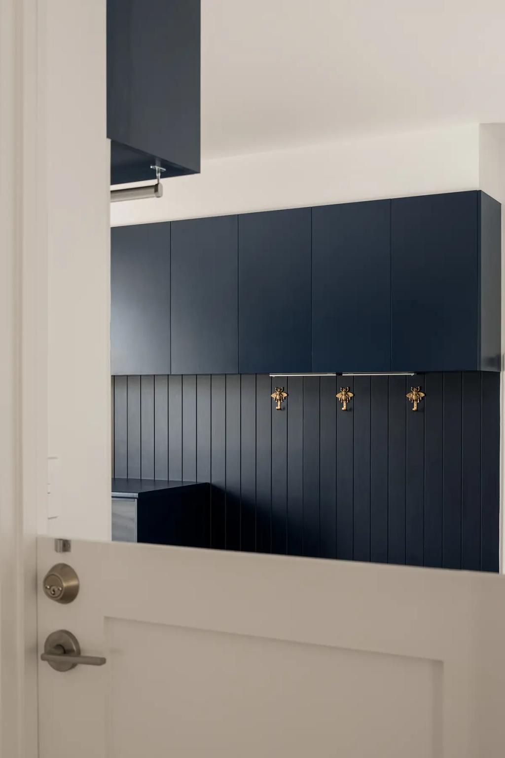 Cheltenham (Mudroom with navy cabinets and gold wall hooks)