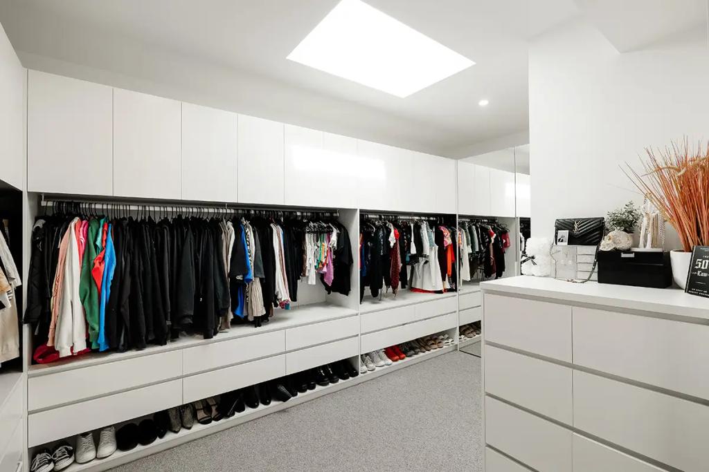 Project Vuse (Spacious and modern walk-in closet with white cabinets, drawers, and shelves filled with clothes and shoes)