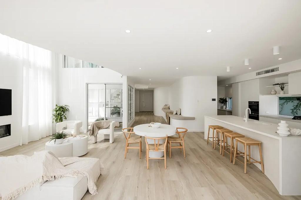 Project Vuse (A modern, open-plan living and dining area with light wooden flooring, white walls, and large windows with sheer curtains)