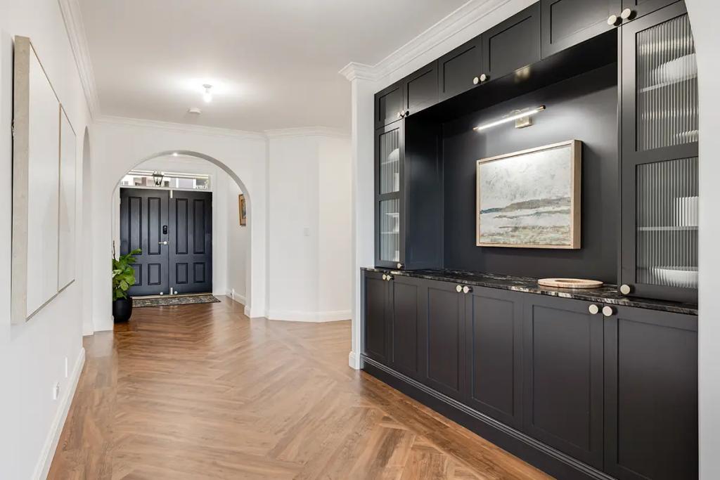 Hodgsonvale House Renovation (A hallway with herringbone wood floors, a dark built-in cabinet, and a black front door.)