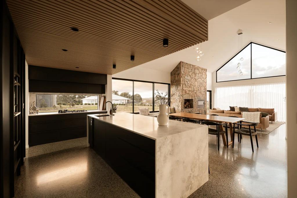 Project Mount Rascal (Open-concept kitchen and living room with marble island, stone fireplace, vaulted ceiling, and large windows)