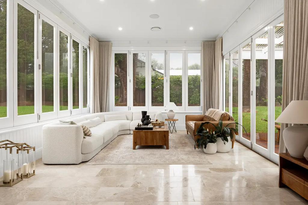 Project Franklin (Sunroom with wraparound windows, white sectional and tan sofa.)