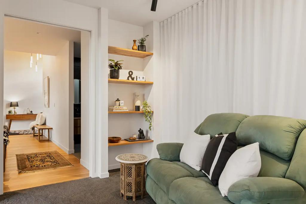 Project Treevue (A cozy living room with a green couch, wooden side table and floating wooden shelves on the wall)