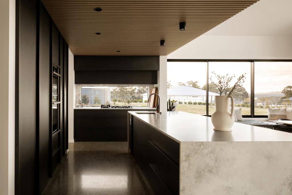 Project Mount Rascal (Modern kitchen with black cabinetry, marble countertops, and large windows offering a scenic outdoor view)