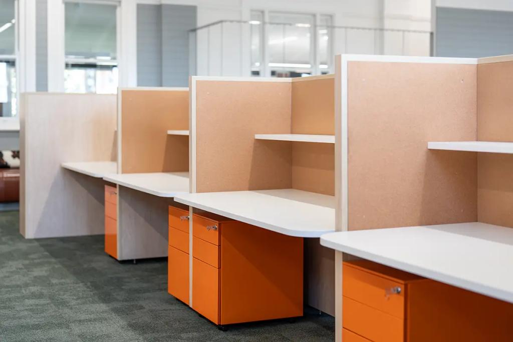 Downlands College Toowoomba Refurbishment (Row of clean office cubicles with corkboard dividers, white desktops, and orange filing cabinets.)