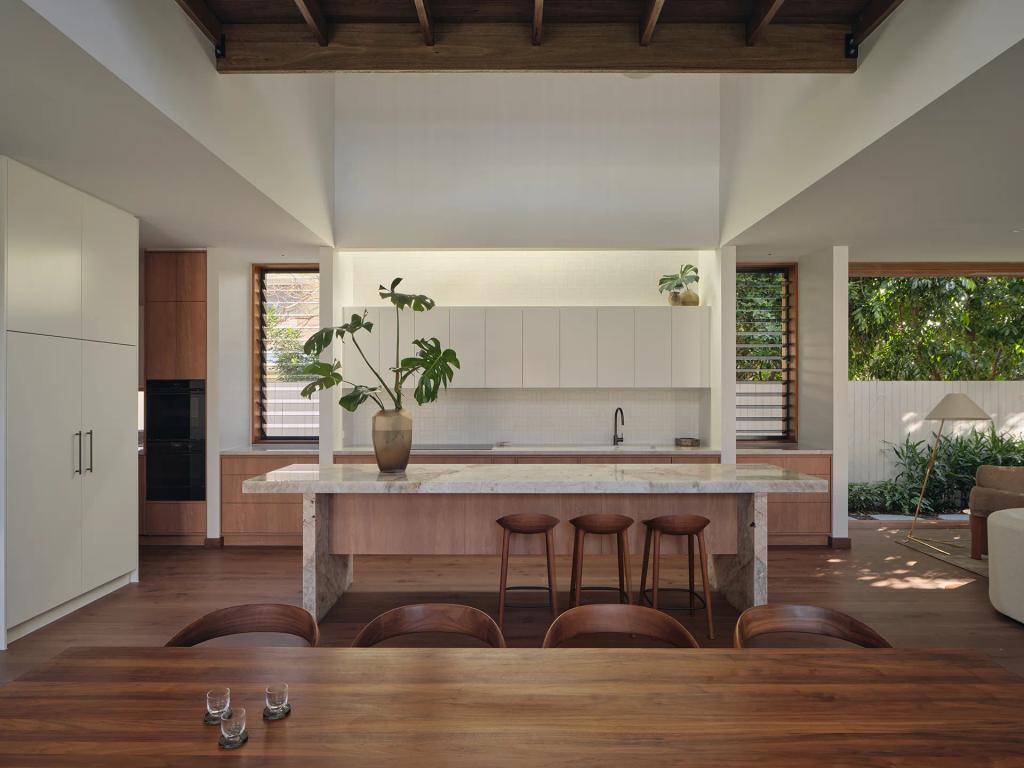 Project Riverton (Modern kitchen and dining area with a stone island, white cabinets, and wood accents under a vaulted ceiling.)