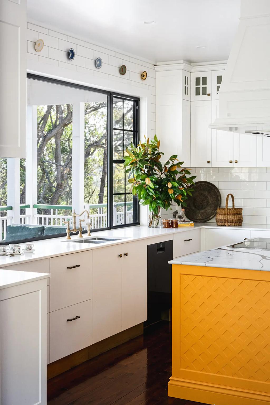 Project Coral Sea (Modern white kitchen with large window, yellow island, marble countertops, and decorative wall plates)