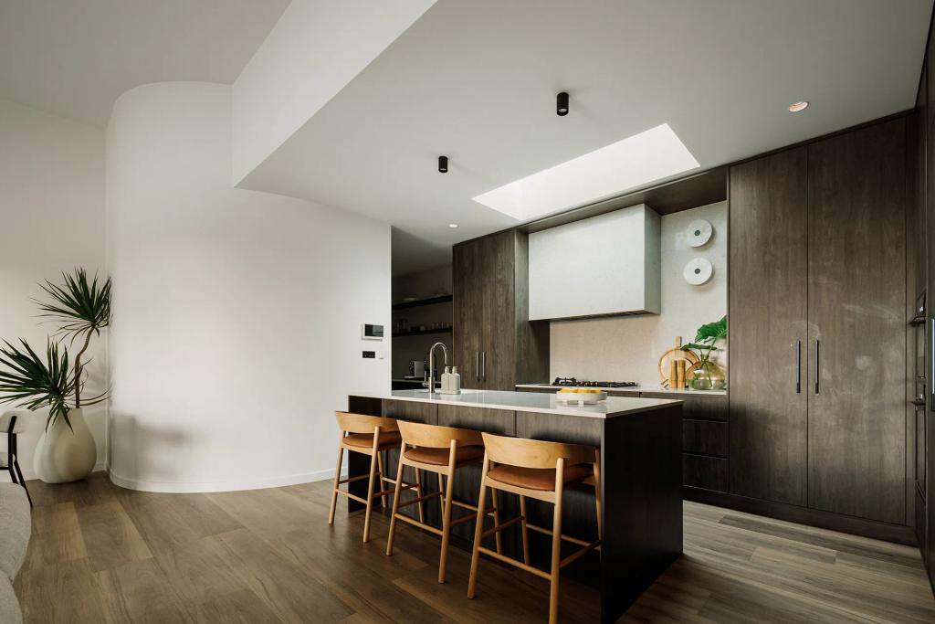 Lavish Morada (Sleek kitchen with wood cabinetry, island seating, skylight, and decorative green accents.)