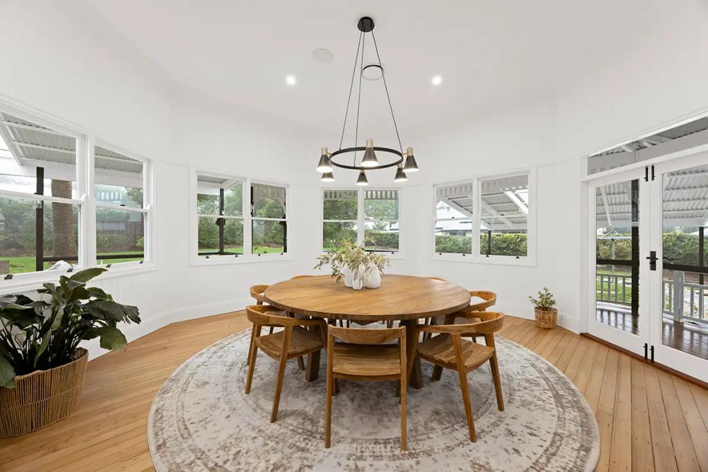 Project Franklin (Round wood dining table with six chairs in sunroom setting.)