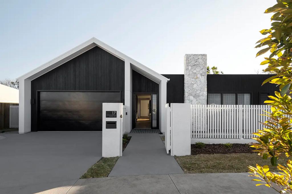Project Ward 2.0 (A modern home exterior with a black garage door, white fence, stone chimney, and a minimalist design)