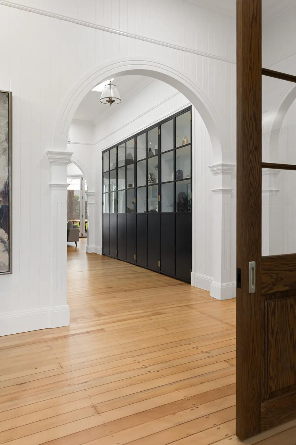 Project Franklin (Arched hallway with black glass-front cabinets and timber floor.)