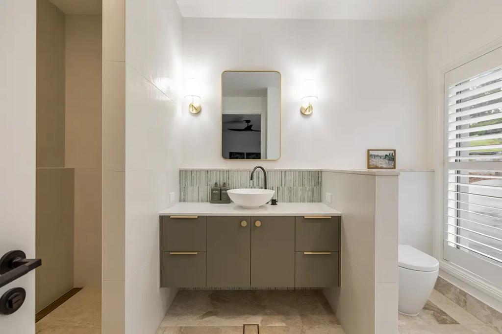 Hodgsonvale House Renovation (A stylish bathroom with a floating green vanity, vessel sink, and rectangular mirror.)