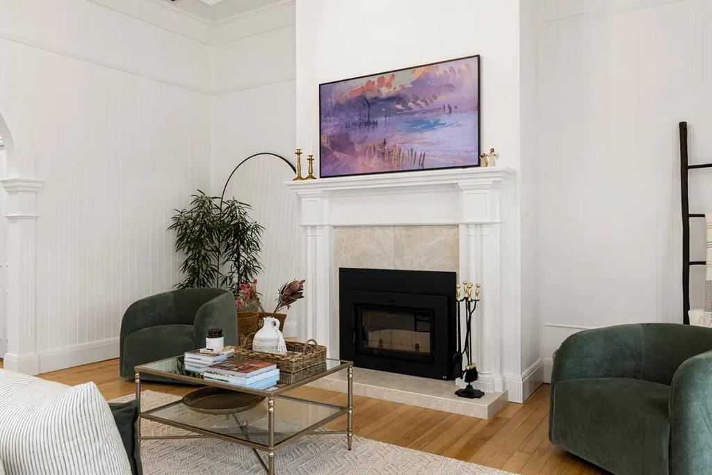 Project Franklin (White fireplace with landscape art framed by green chairs.)