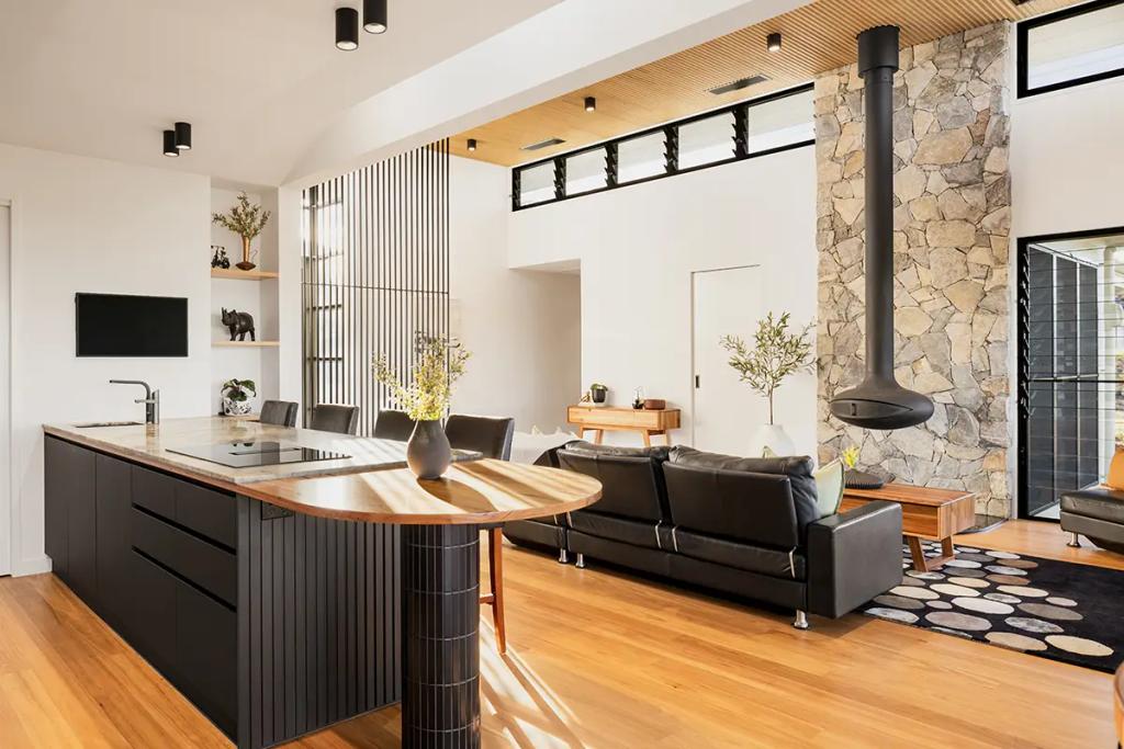 Project Treevue (Modern open-plan living room with wooden floors, a black kitchen island with marble top, a black leather couch, a hanging fireplace, and a stone feature wall)