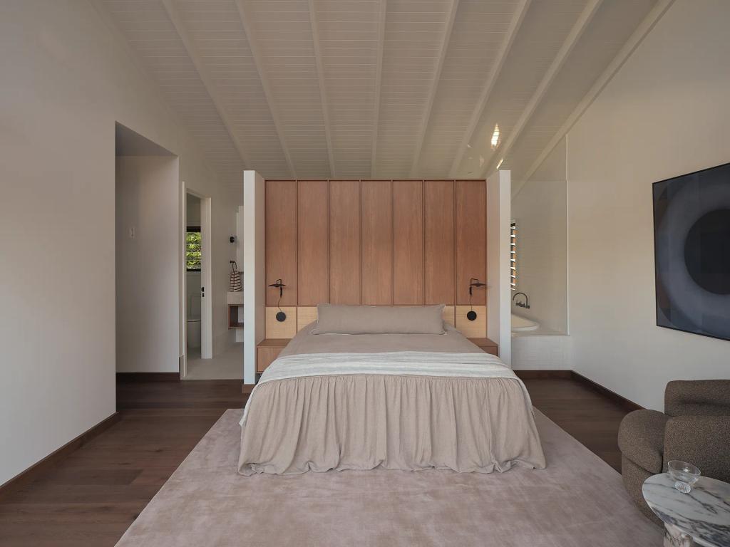 Project Riverton (Open-concept primary bedroom with a wood-paneled headboard, neutral bedding, and a vaulted ceiling.)