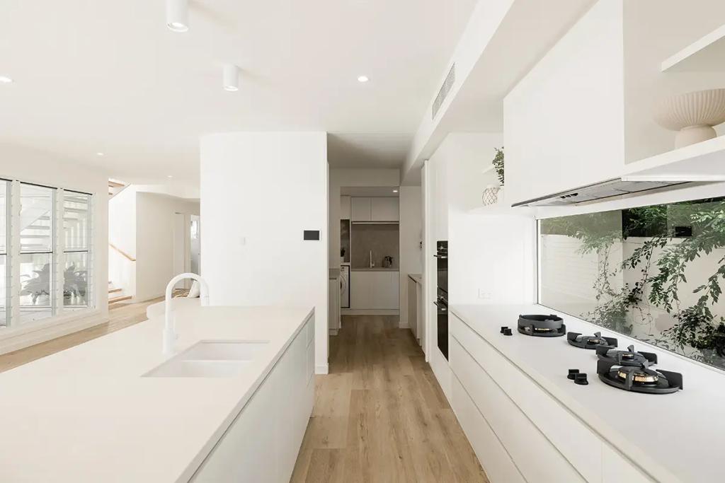 Project Vuse (A modern kitchen with white cabinets, a kitchen island with a sink, and a gas stove top)