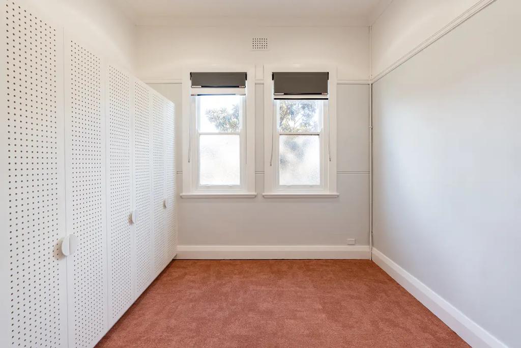 Downlands College Toowoomba Refurbishment (Simple room with reddish carpet, two frosted windows, and a row of white perforated storage lockers.)
