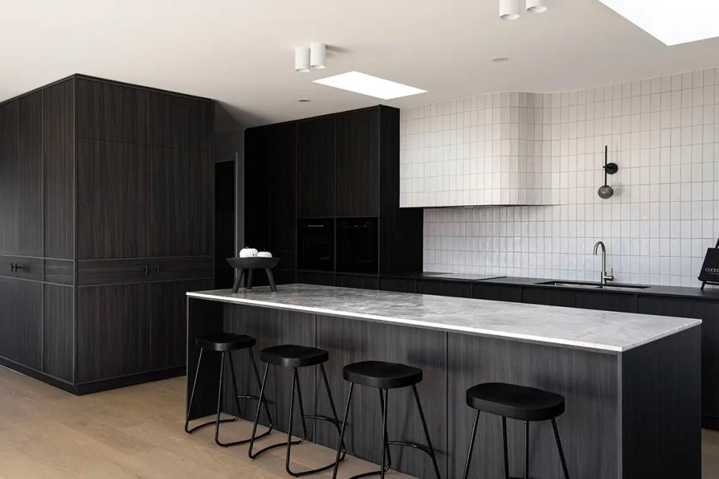 Project Ward 2.0 (Modern kitchen with dark wood cabinets, a marble island, black stools, and a white tiled backsplash)