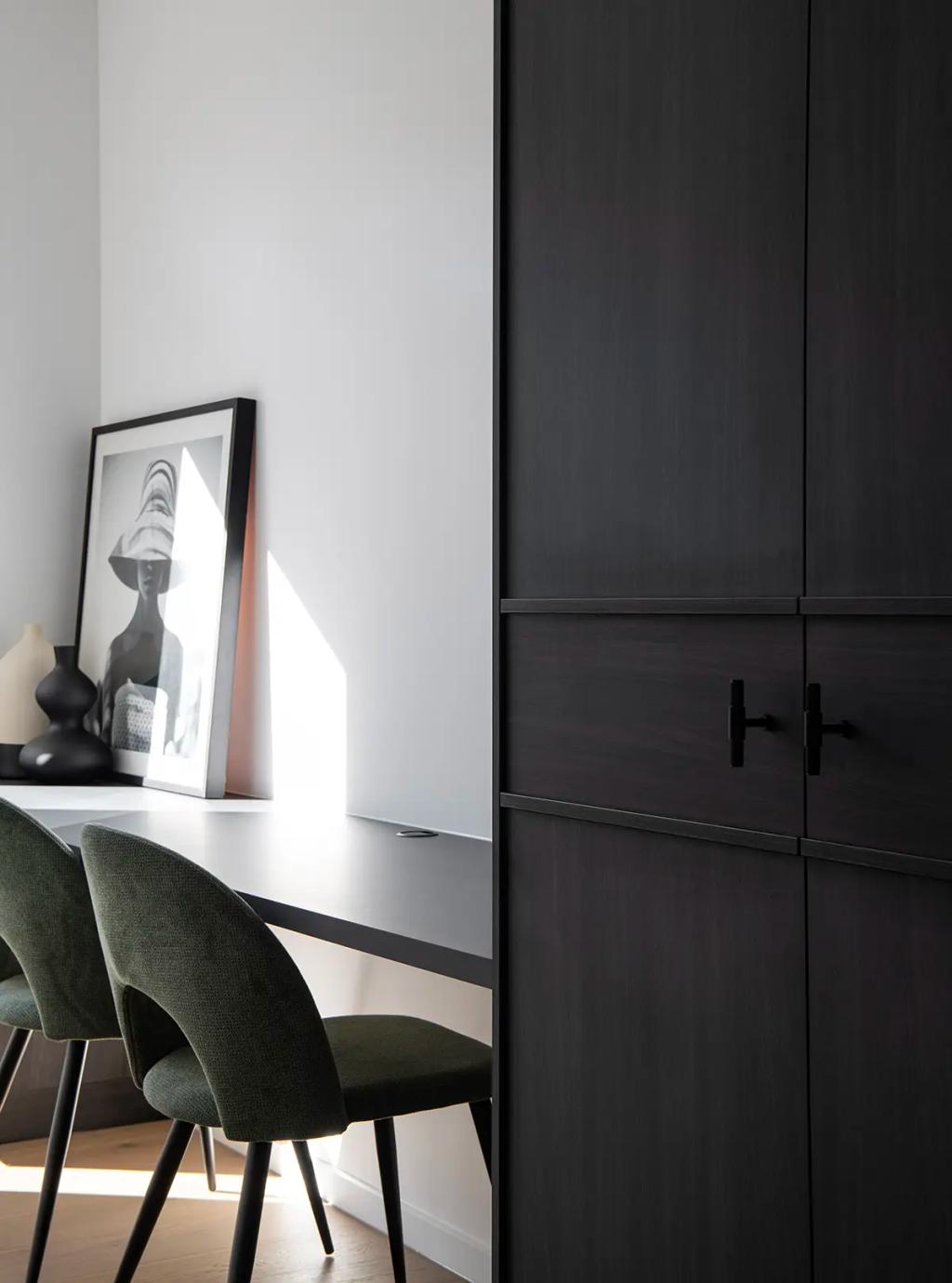 Project Ward 2.0 (A modern home office with dark wood cabinetry, a sleek black desk, green upholstered chairs, and framed art)