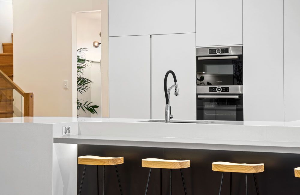 Project Bobbie (White island with black base, timber stools and floor-to-ceiling white cabinetry)