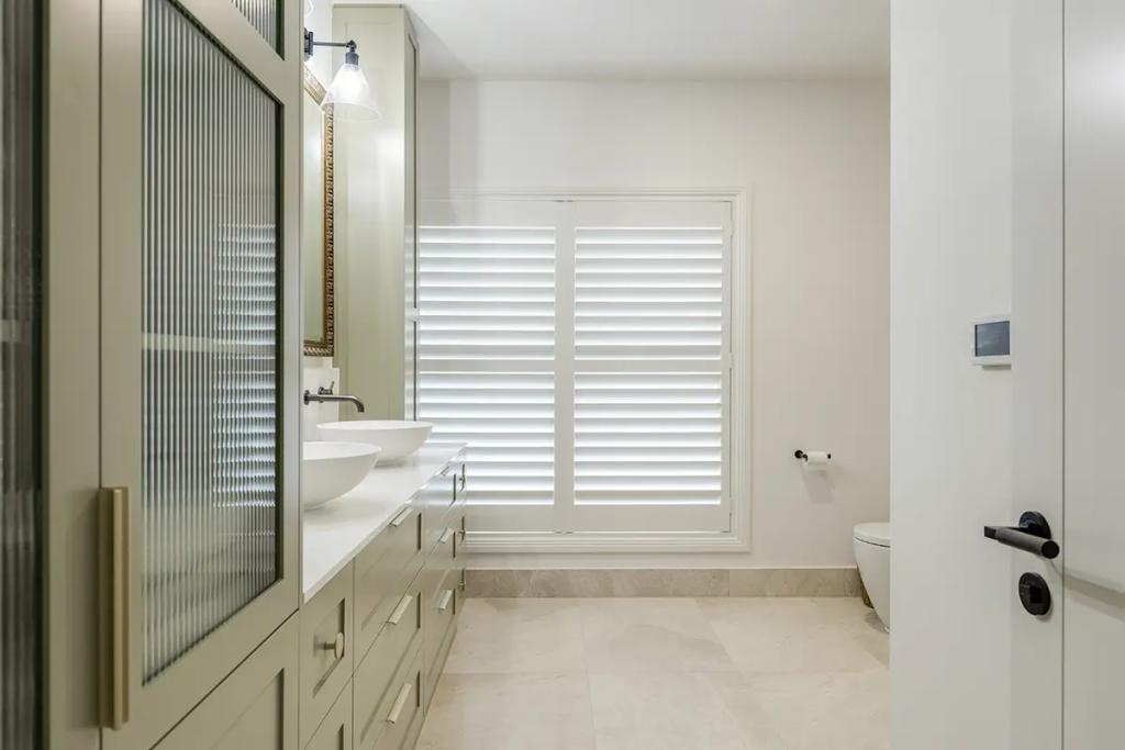 Hodgsonvale House Renovation (A bathroom with a long green vanity, dual sinks, shuttered window, and toilet.)
