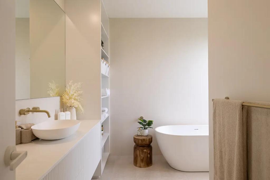 Project Vuse (Modern bathroom with a white freestanding bathtub, beige walls, a floating sink vanity with brass faucet)