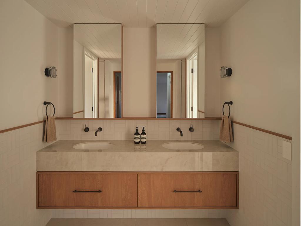 Project Riverton (Bathroom vanity with a floating wood cabinet, double marble sinks, and two vertical mirrors.)