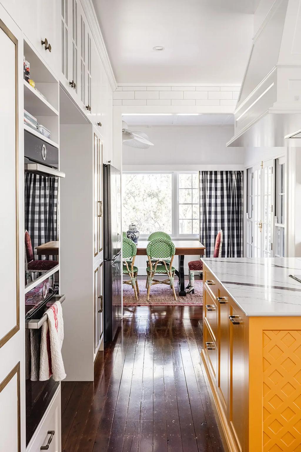 Project Coral Sea (Kitchen with yellow island, marble countertop, and view into dining area with green chairs and windows)