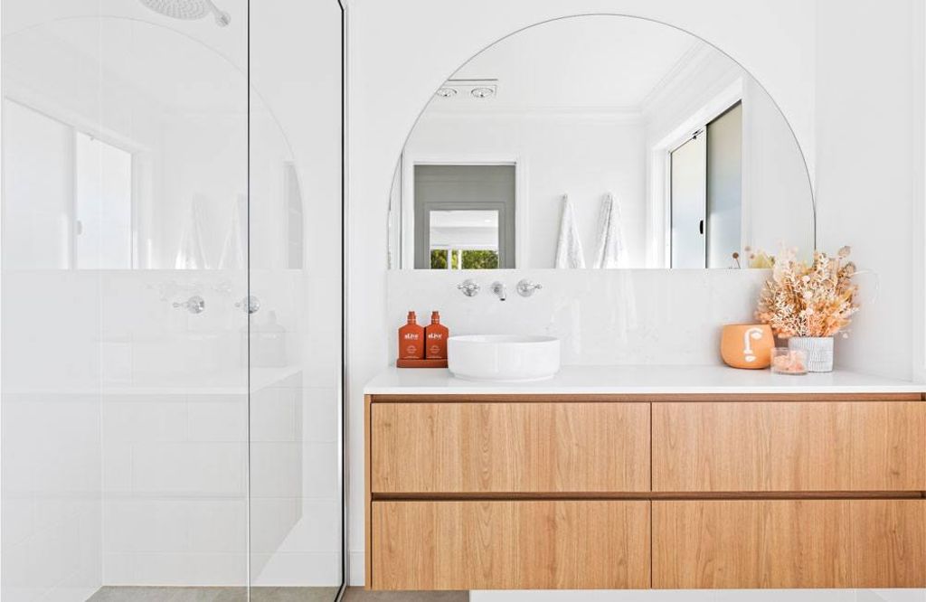 Project Campbell (half view of bathroom shower area and sink with wooden cabinet and half circle mirror)