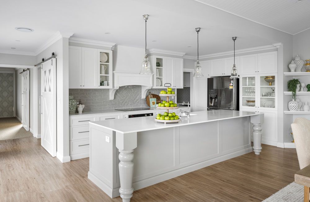 Queenie Marlow (White Hamptons kitchen with turned-leg island, herringbone splashback and glass pendants)