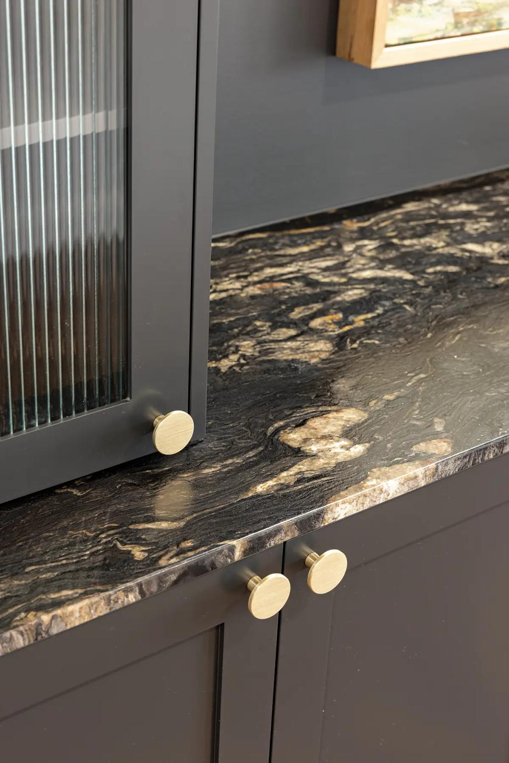 Hodgsonvale House Renovation (Close-up of a dark cabinet with reeded glass, gold knobs, and a granite countertop.)