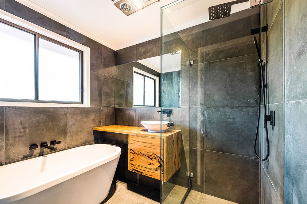 Project Marri (Bathroom with dark wall tiles, timber vanity, white freestanding bath and glass shower)
