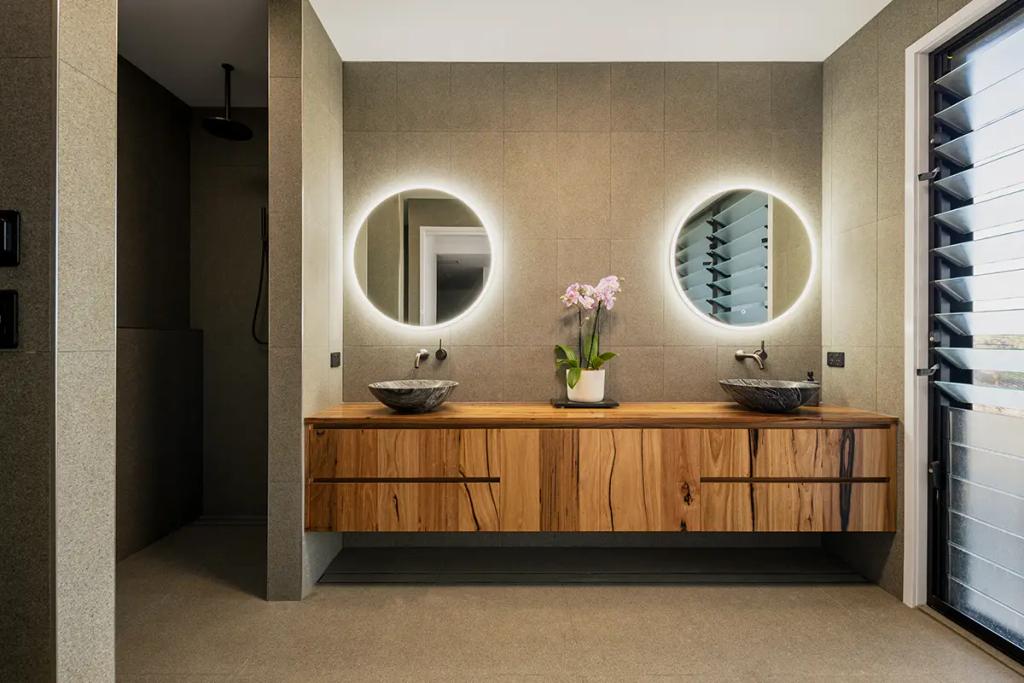 Project Treevue (A modern bathroom with a wooden vanity and two round mirrors with backlighting)