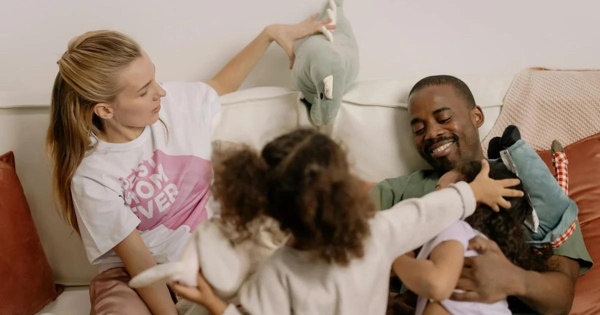 A modern family, including parents and children, engaging with various smart home AI devices like a voice assistant, a smart screen, and automated lighting in a warm, futuristic living room.