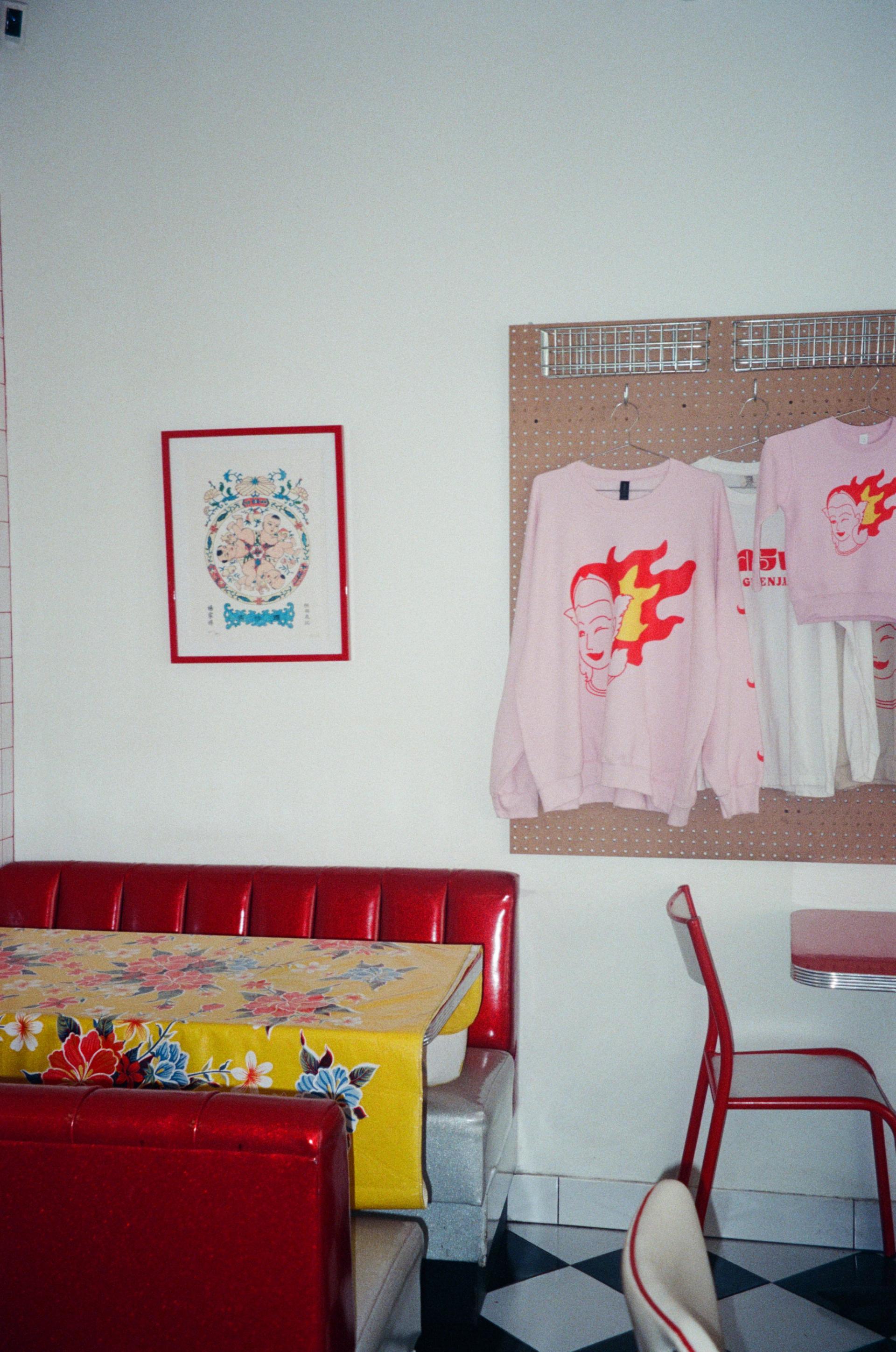 Red diner corner booth with Little Grenjai merch and art from Bangkok.