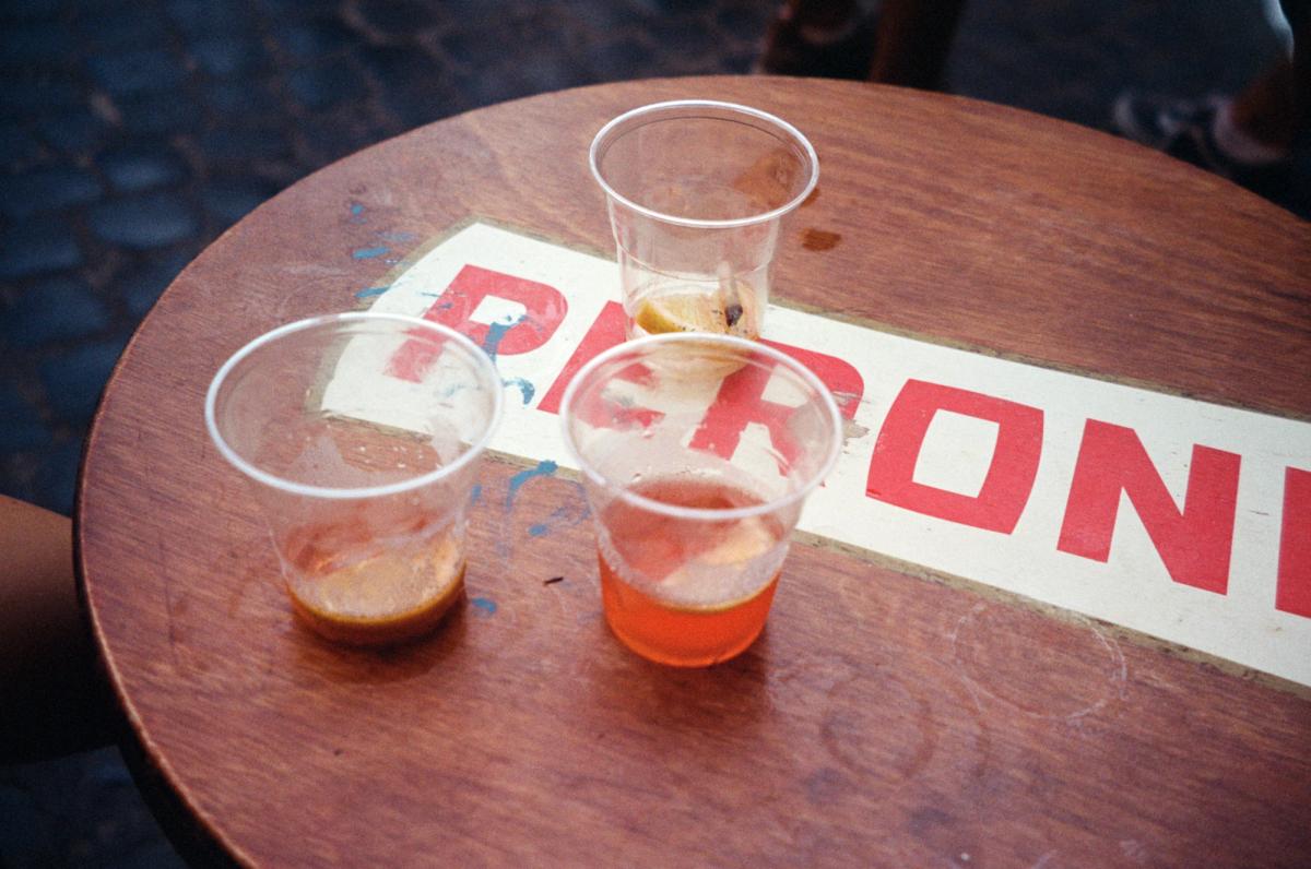 Aperol spritzes in plastic cups on an old Peroni branded table.