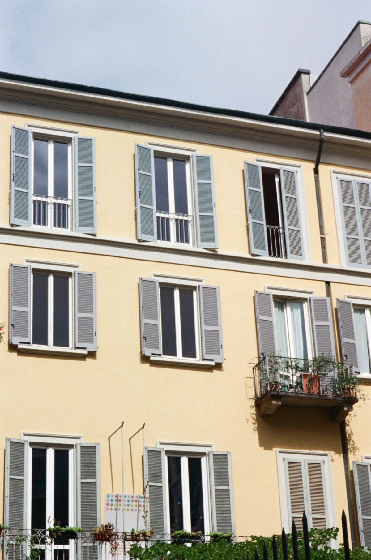 Yellow building with blue shades in Milan.