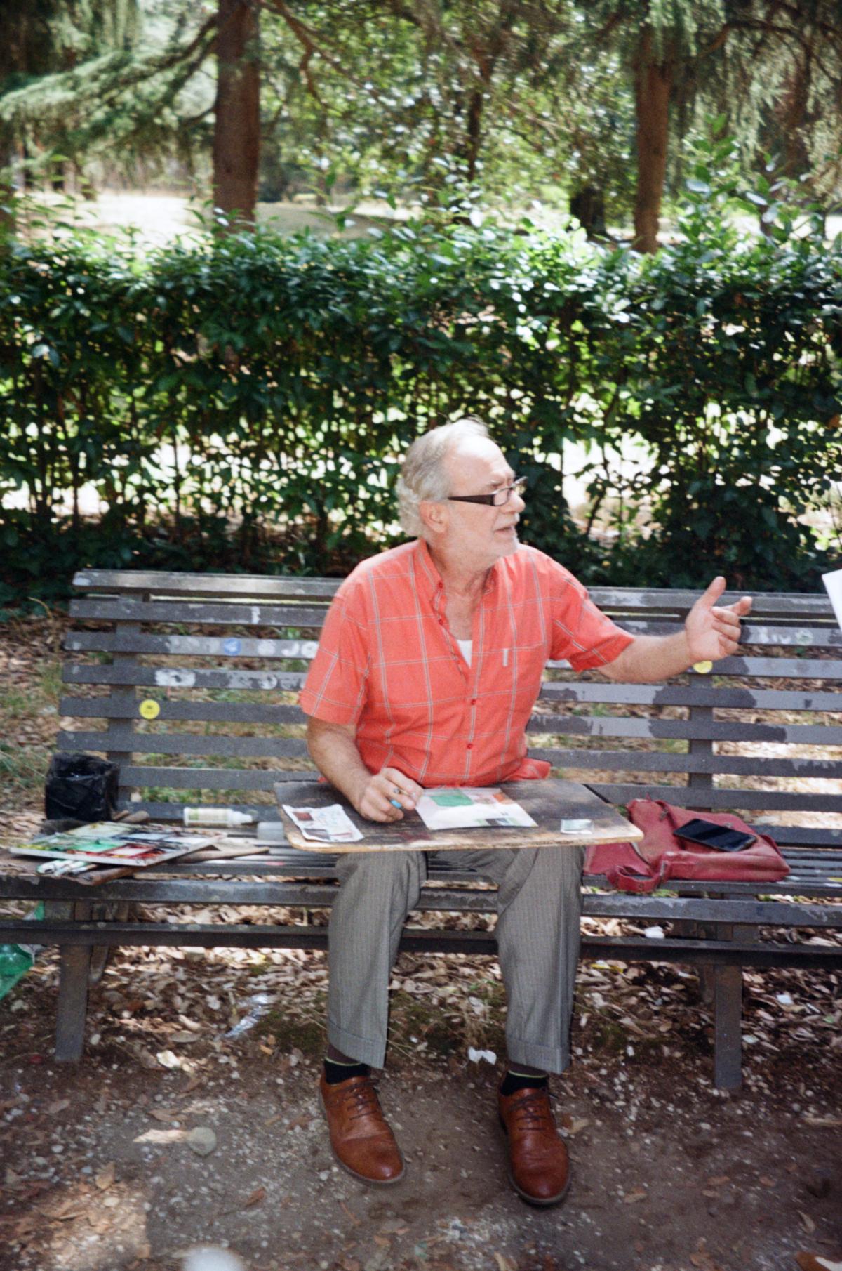 Italian artist on a bench with his water colors and painting supplies.