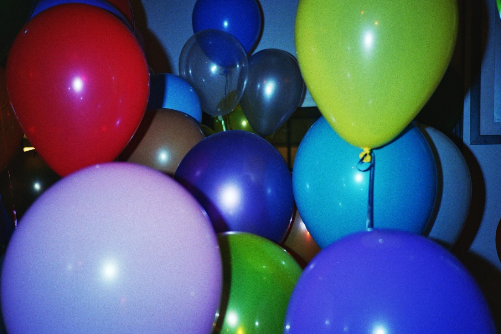 a bunch of colorful balloons are sitting on top of each other in a room .