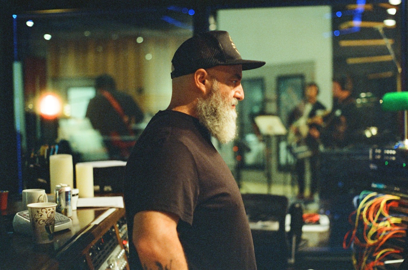 a man with a beard and a hat is standing in a recording studio .