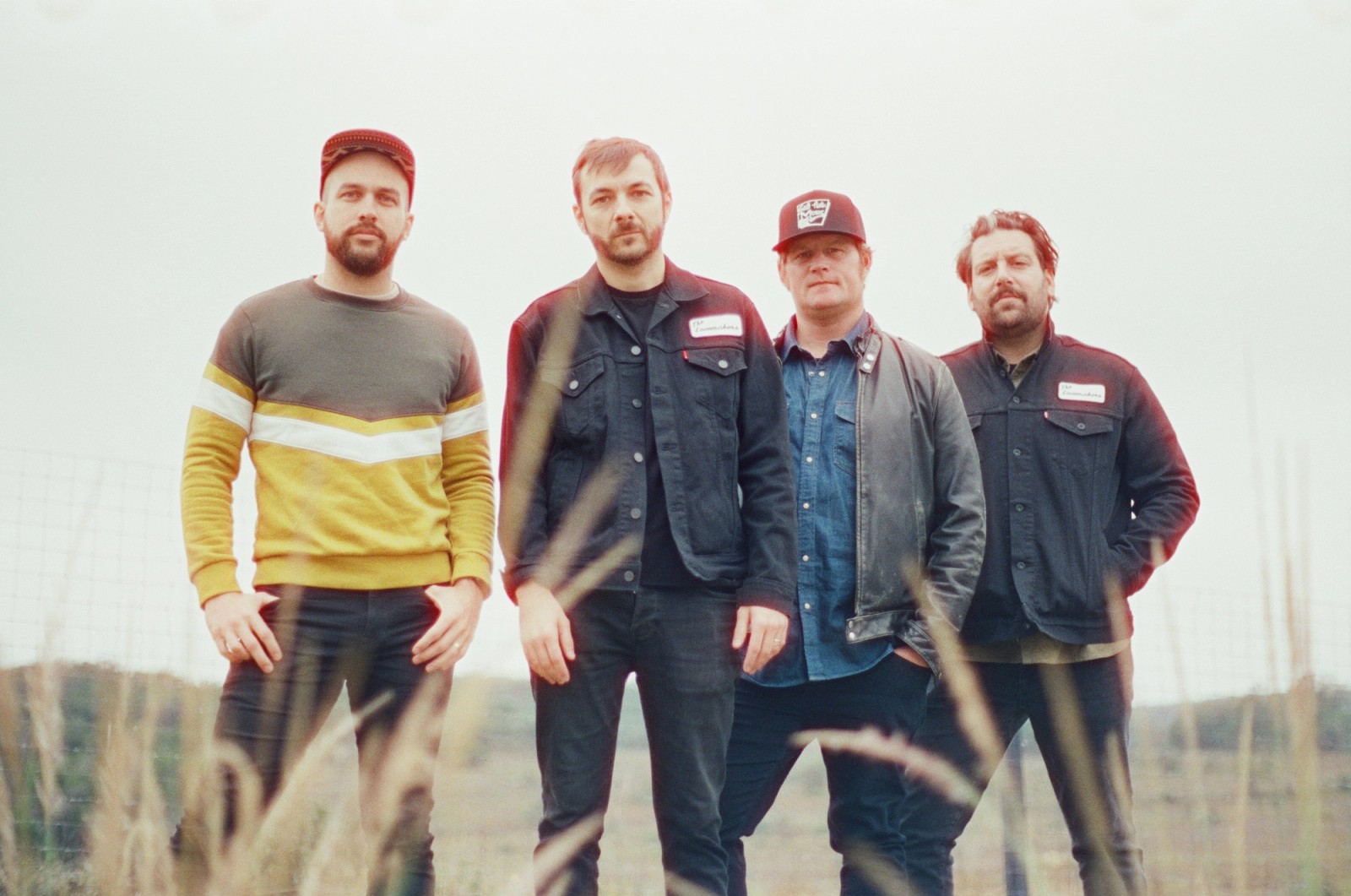 a group of men are standing in a field of tall grass .